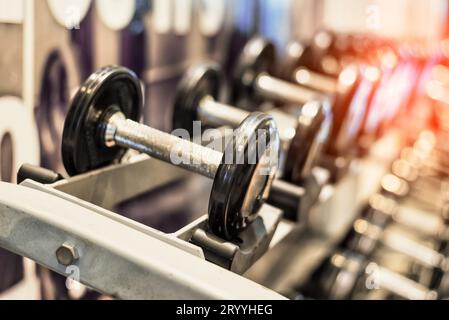 Close up of black metallic steel dumbbell set. Dumbbells on rack in sport fitness center. Workout training and fitness gym conce Stock Photo
