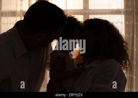 Parents and children enjoy the morning sunlight shining through the bedroom window in the house. Stock Photo