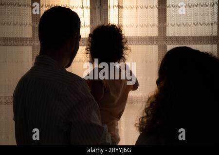 Parents and children enjoy the morning sunlight shining through the bedroom window in the house. Stock Photo