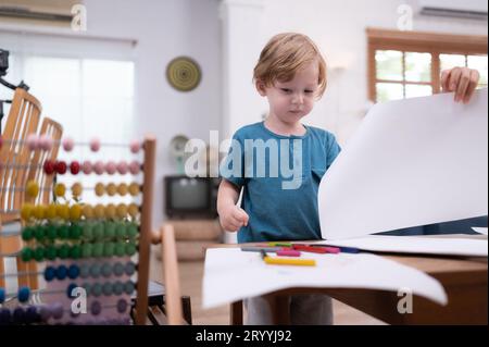 A little child's imagination is represented through colored pencil drawings, with the mother attentively supervising in the livi Stock Photo