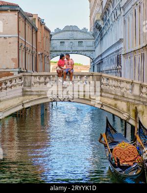 Couple of men and women on a city trip in Venice Ital sitting at waterfront of the bridge of sighs Stock Photo