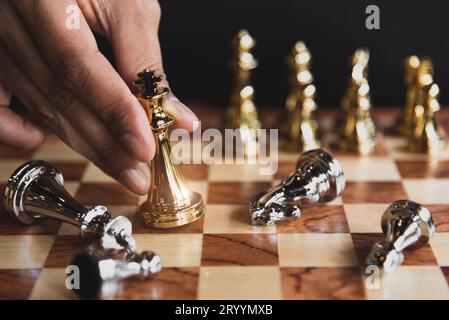 Hand of businessman moving golden chess figure for eliminating in battle competition with last successful ending game. Leadershi Stock Photo
