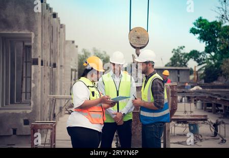 Group of architects, construction foremen, and construction engineers review the work and talk about how the project, in the con Stock Photo