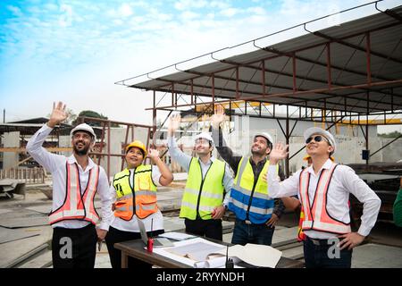 Construction engineers, architects, and foremen form a group. Participate in a meeting to plan new construction projects. Cheers Stock Photo