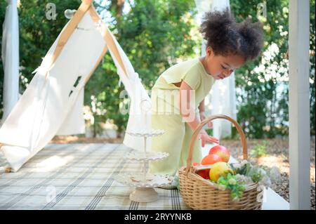 A bright and cute little girl with fun playing in the garden of the house. Stock Photo