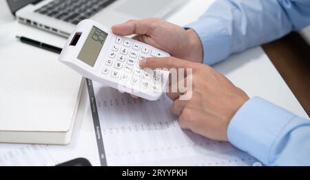 Businessman Accountant analyzing investment charts Invoice and pressing calculator buttons over documents. Accounting Bookkeeper Stock Photo