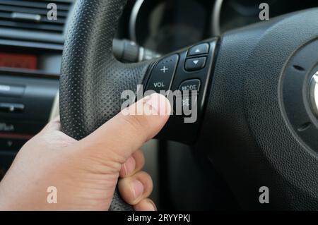 Man driving hands pushing button on the steering wheel in the car selective focus. safety driving concept Stock Photo