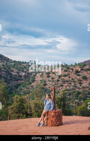 Little girl on the edge of a cliff at Cathedral Rock in Sedona, Arizona. View from Scenic Cathedral Rock in Sedona with blue sky Stock Photo