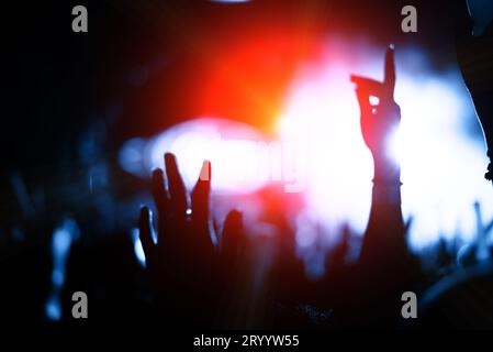 Silhouette crowd audience in concert with hands raise at music festival and colorful lighting stage. Entertainment and Relax act Stock Photo