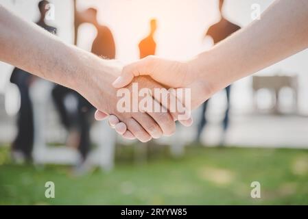 Handshake of two business people at outdoors. Business and Nature concept. Meeting and Partnership theme. Blurry people in backg Stock Photo