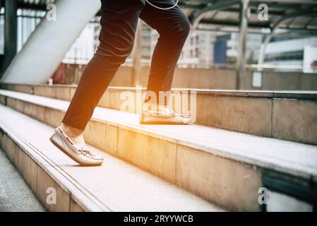 Close up legs of traveling people walking on stepping up stair in modern city. Sneakers and jeans elements. Business and travel Stock Photo