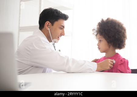 Hispanic physician meeting and diagnosis mixed-race afro children with her African American mother at a hospital. The doctor using stethoscope and do Stock Photo