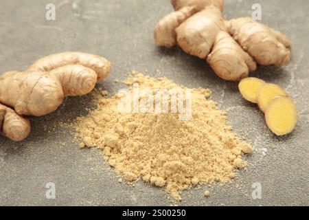 Ginger powder with fresh ginger root on grey concrete background. Stock Photo