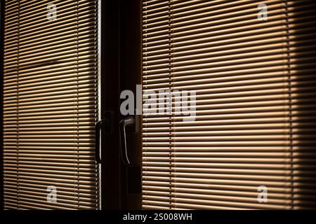 Blinds on the window. Light through the blinds. Window in the room. Stock Photo