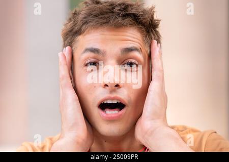Portrait individual Shocked Young Man Holding His Face Stock Photo