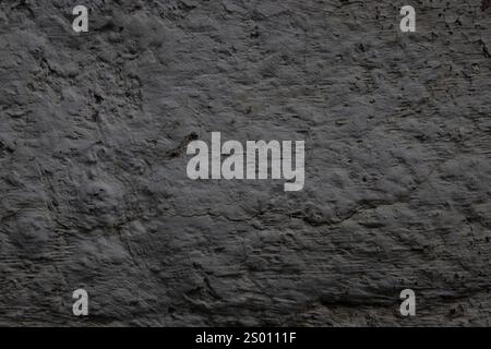 Close-up of a rough gray concrete wall displaying its natural texture and visible cracks, showcasing industrial aesthetics. Stock Photo