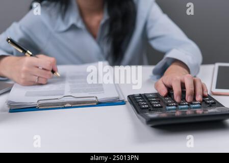 A woman calculates and writes on documents, representing budgeting, accounting, or financial planning. Perfect for illustrating business financial man Stock Photo