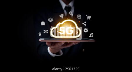 Businessman presenting a glowing 5G cloud symbol over a tablet, representing next-gen wireless technology and fast connectivity. Concept for data, mob Stock Photo