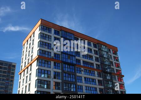 A very tall and modern building adorned with numerous large windows standing prominently against a bright blue sky, creating a striking view Stock Photo
