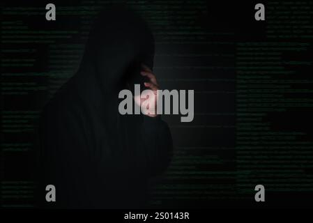 Hacker in a dark environment making a secret phone call, representing cybercrime, identity theft, and digital threats. Ideal for cybersecurity, hackin Stock Photo