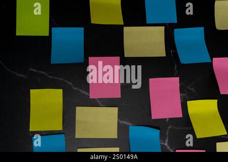 Colorful sticky notes arranged on black surface for creative idea organization. Aerial view. Stock Photo