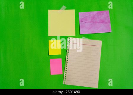 Different blank note papers of different sizes, colors and shapes on a green surface. Landscape orientation Stock Photo
