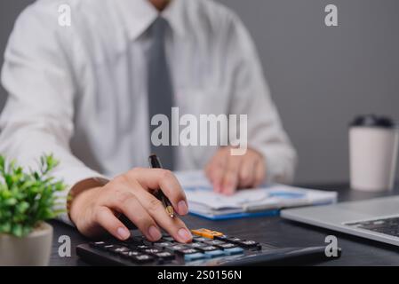 hand using calculator while reviewing financial documents, evoking focus and precision. Ideal for accounting, Stock Photo
