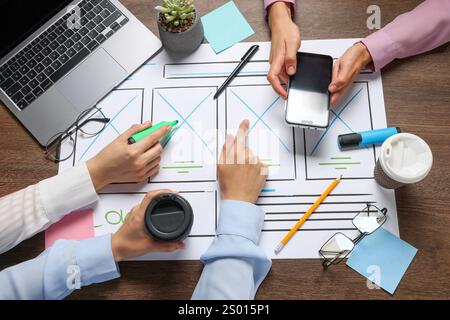 Developing UI design. Designers creating website wireframe on paper at wooden table, top view Stock Photo