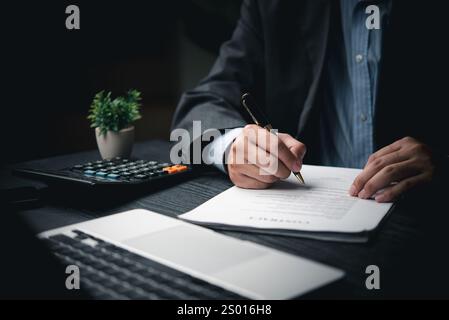 A man is holding a pen, writing or checking a report, working document or doing accounting on a desk. Stock Photo