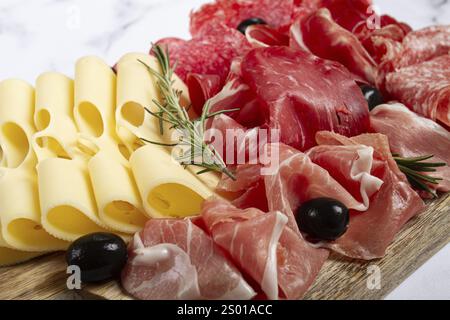 Assorted meat, appetizer, prosciutto, salami and ham, with maasdam cheese and olives, on a wooden board, breakfast, top view, close-up, no people Stock Photo