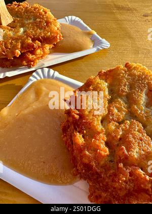 Two Potato pancakes with apple sauce on paper plates on a wooden table Stock Photo