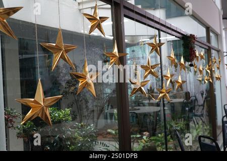 Golden Christmas stars hanging on a window pane with selective focus Stock Photo