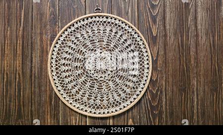 Crochet napkin on a wooden frame. Mandala with different patterns Decor Handmade Wooden background Stock Photo