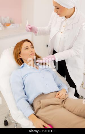 A dedicated practitioner carefully performs dermal filler therapy on a client in a bright and welcoming clinic. Stock Photo