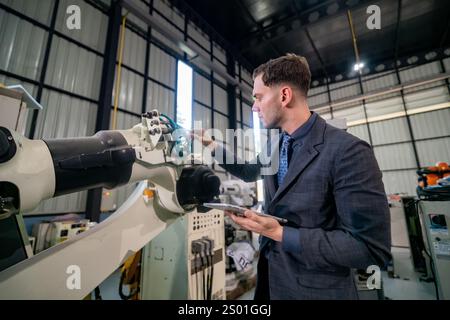 A professional in formal attire inspects a robotic arm in an industrial setting, focusing on its mechanical parts. The bright environment enhances the Stock Photo