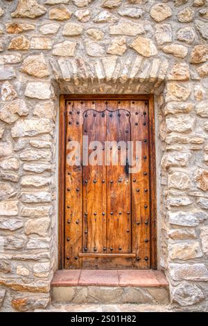 Old rustic medieval wooden door on a stone building in Spain Stock Photo