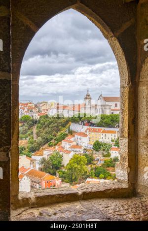 Skyline view of the rooftops of the historic district of Lisbon, Portugal through a gothic arched window Stock Photo