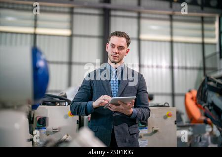 An aerial view captures a professional assessing industrial equipment while using a tablet in a modern facility. The environment showcases advanced ma Stock Photo