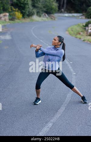 Young slim female warming up her body on an abandoned empty road Stock Photo