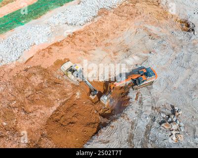 Large tracked excavator with hydraulic hammer breaks asphalt at a construction site Stock Photo