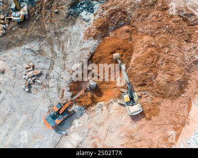 Large tracked excavator with hydraulic hammer breaks asphalt at a construction site Stock Photo