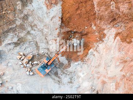Large tracked excavator with hydraulic hammer breaks asphalt at a construction site Stock Photo
