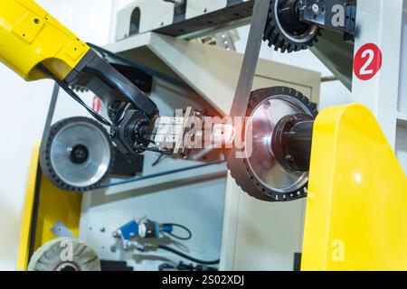 robotic arm handling the metal machined shaft parts polishing between the production line. automotive parts manufacturing process. Stock Photo