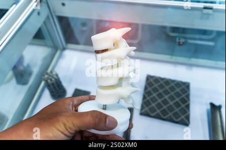 hand with 3d printed human spine in 3d printer. Stock Photo