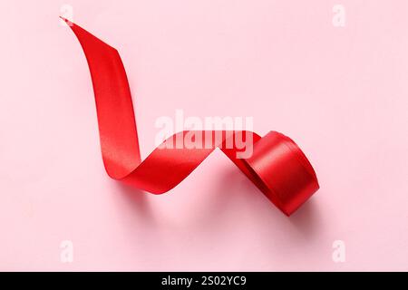Rolled red ribbon on pink background Stock Photo