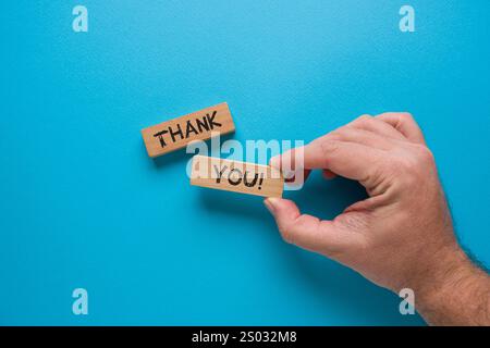 Thank you is written on wooden blocks standing on a blue background Stock Photo