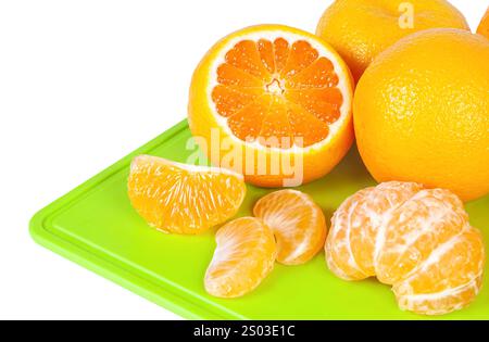 Bright oranges are displayed on a green cutting board, showing whole, sliced, and segmented pieces ready for use in recipes or snacks. Stock Photo