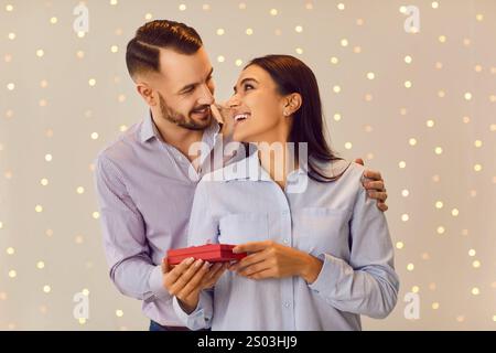 Valentine Day. Happy smiling couple in love standing together with red present gift box and hugging. Stock Photo