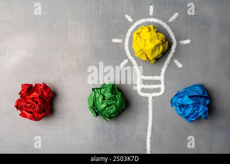 A flat lay image of a lightbulb drawn on a chalkboard with crumpled pieces of paper. Creative process and generation of ideas concept. Stock Photo
