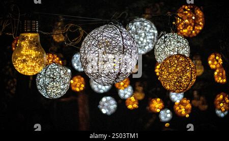 A collection of decorative lights in various shapes and colors, including spherical and bulb forms, glowing warmly against a dark background. Stock Photo